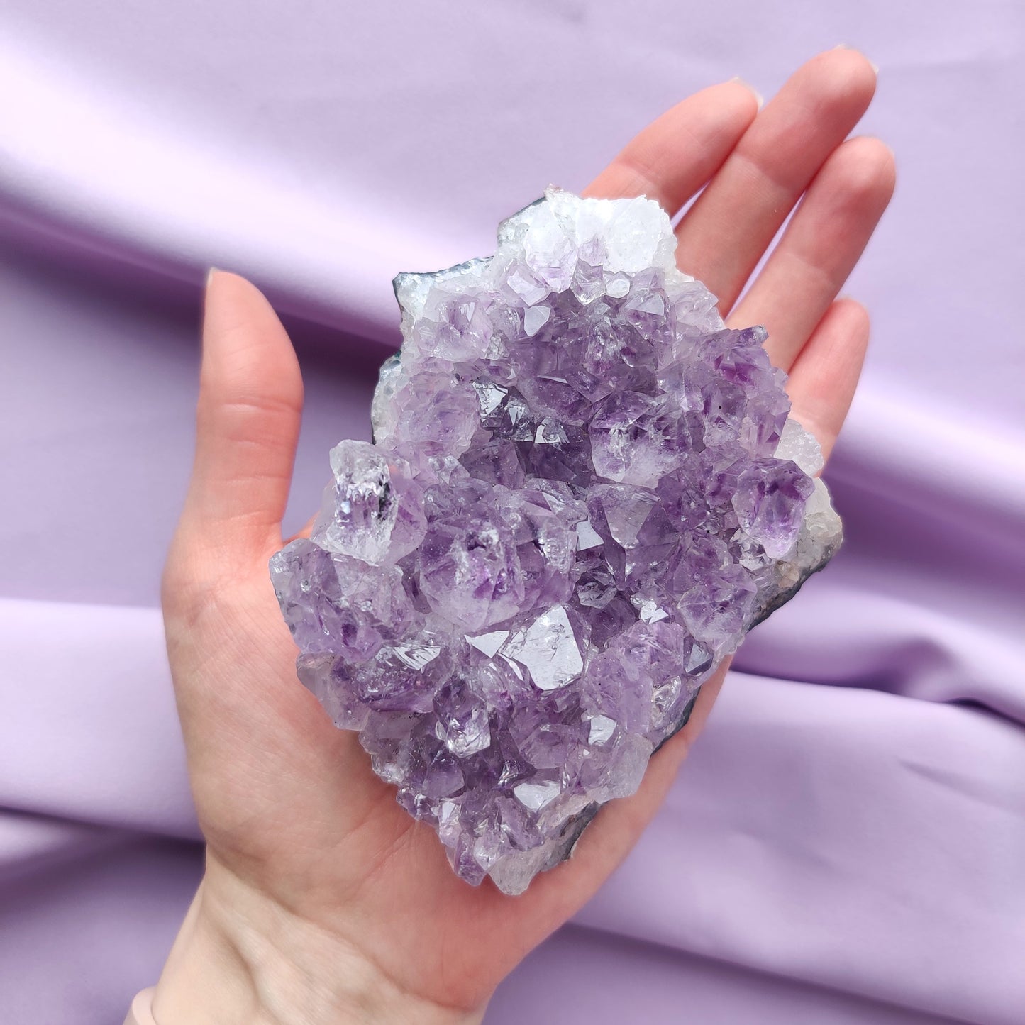 pieni ametistiryväs kädessä violetilla taustalla
