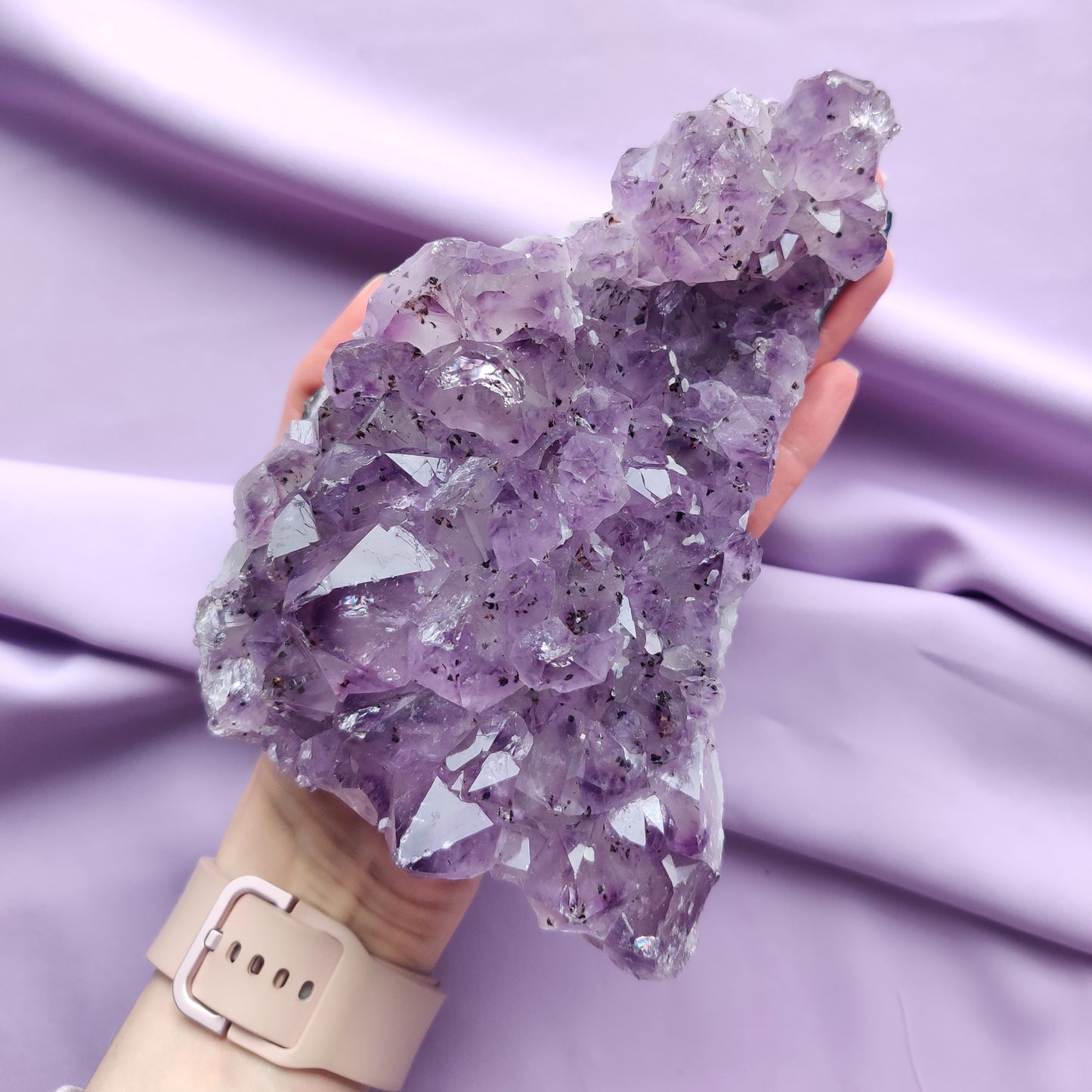 iso ametistiryväs kädessä violetilla taustalla