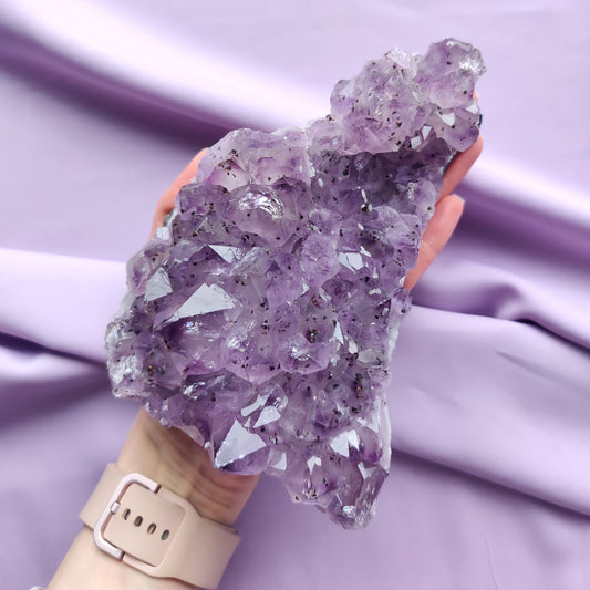 iso ametistiryväs kädessä violetilla taustalla