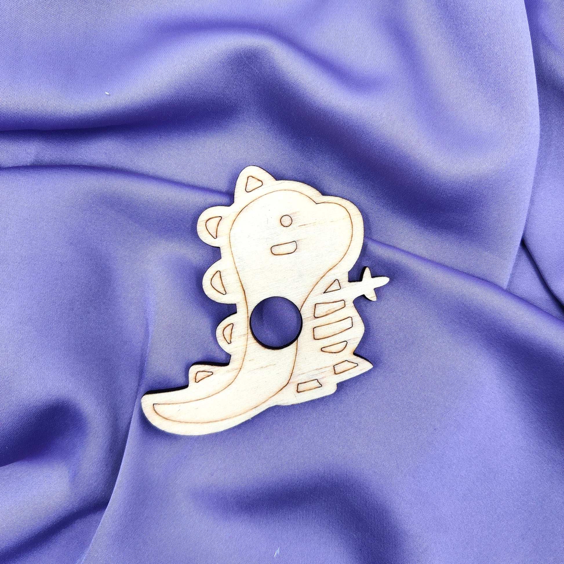 Laserleikattu ja kaiverrettu vanerinen dinosaurus-kivipalloalusta violetilla taustalla