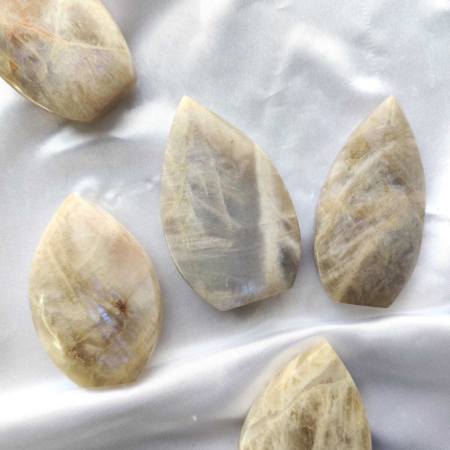 Hohtava kuukivipisara valkoisella silkkikankaalla