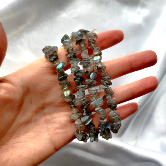 Hohtavat labradoriittti hippurannekorut kädessä valkoisella taustalla