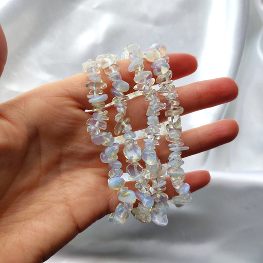 Läpikuultavat opaliitti hippurannekorut kädessä valkoisella taustalla