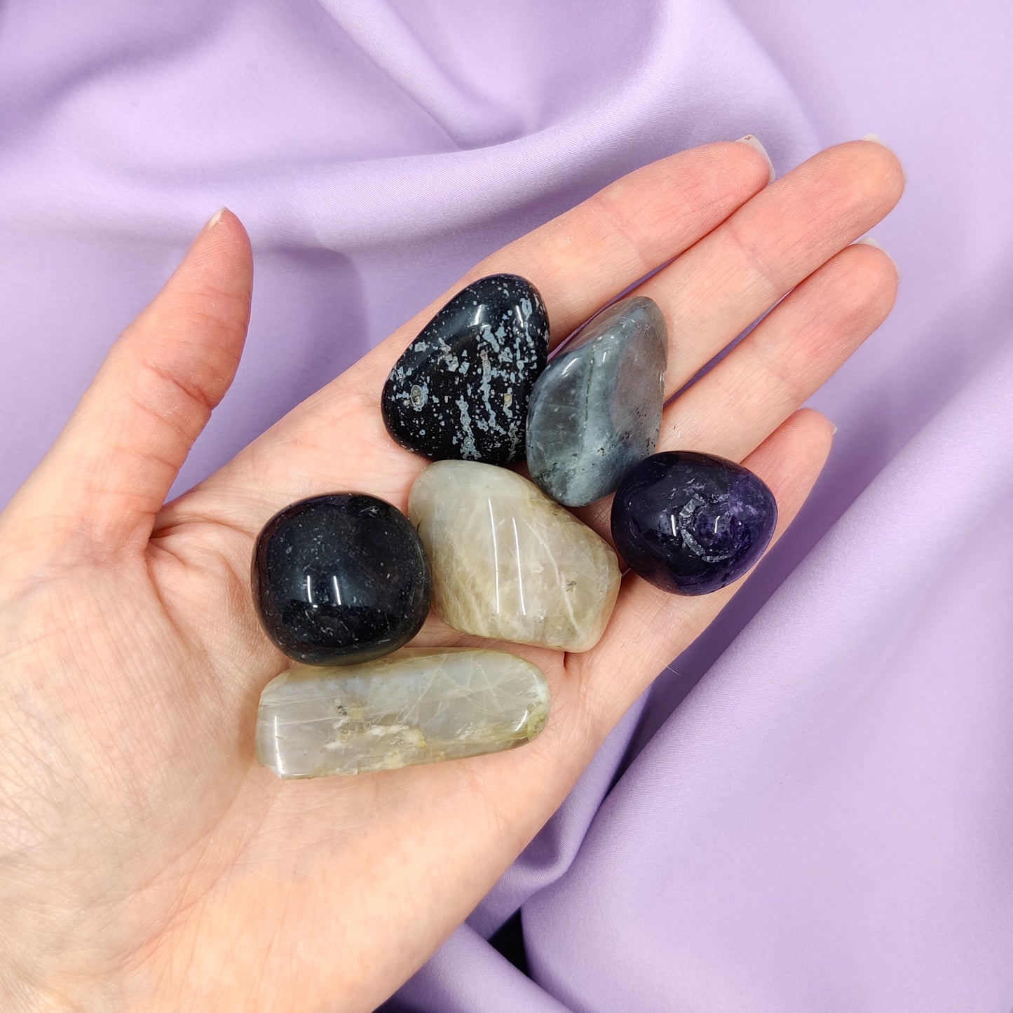 kakkoslaadun rumpuhiottuja kiviä kädessä osassa lohkeamia violetti tausta