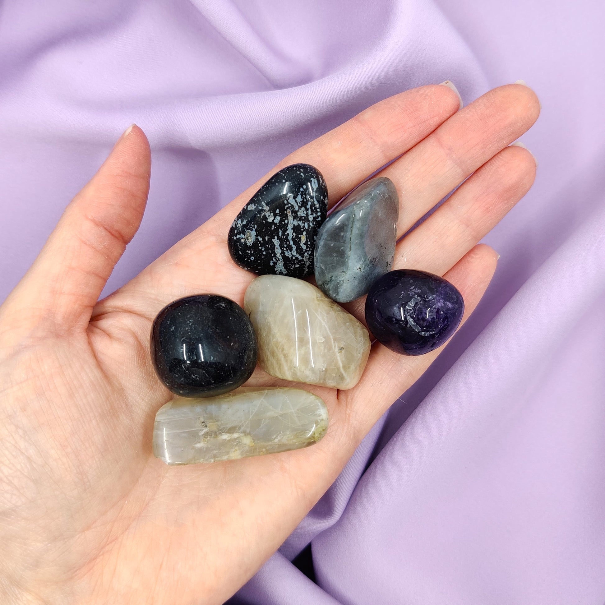 kakkoslaadun rumpuhiottuja kiviä kädessä osassa lohkeamia violetti tausta