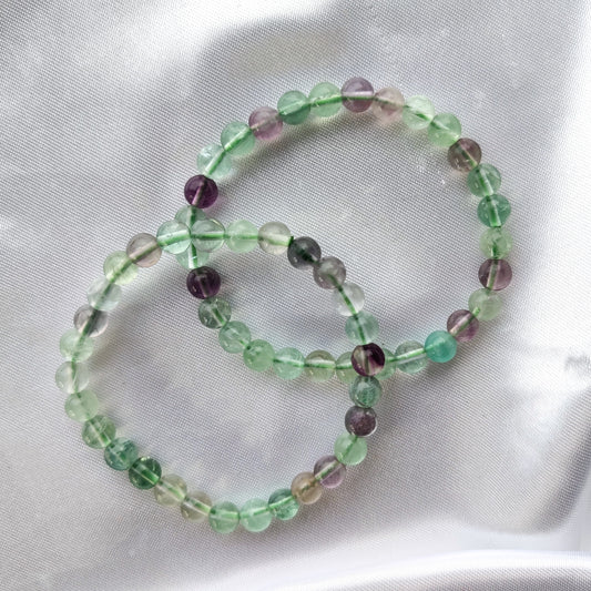 Läpinäkyvät fluoriitti helmirannekorut valkoisella silkkikankaalla