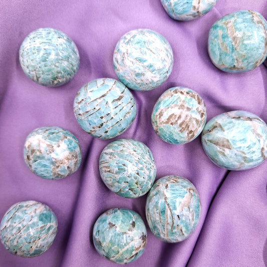 Kirkkaan siniset rumpuhiotut amatsoniitit violetilla silkkikankaalla