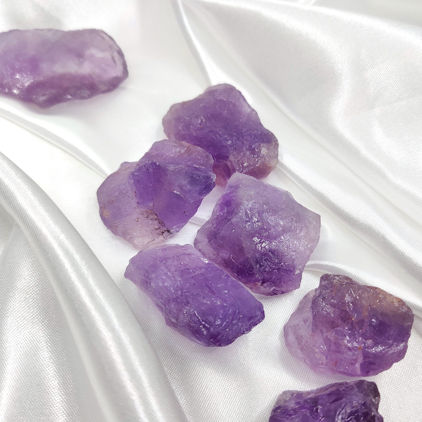 Violetit raaka ametistikivet valkoisella silkkikankaalla