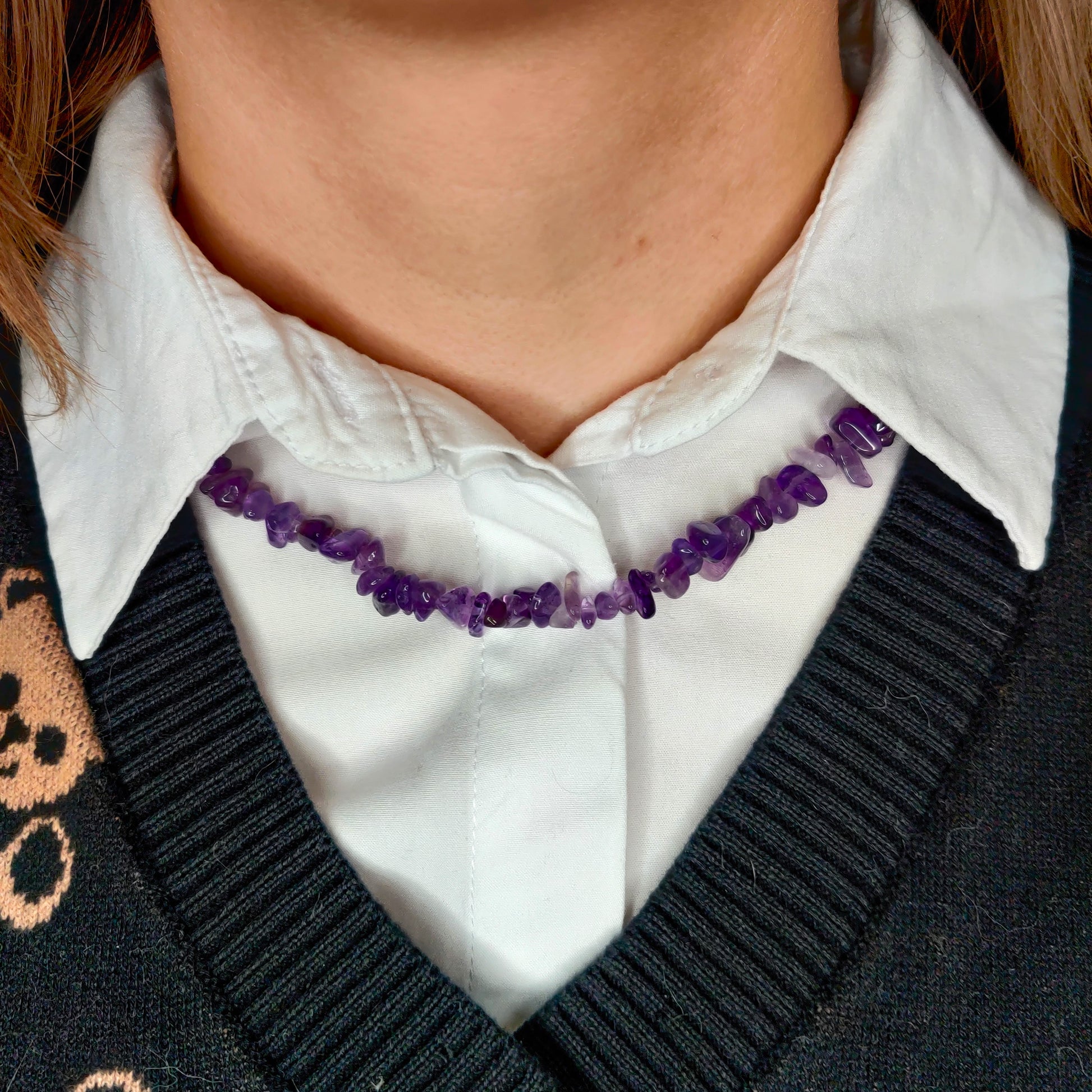 Violetti ametisti hippukaulakoru kaulassa kauluspaidan päällä