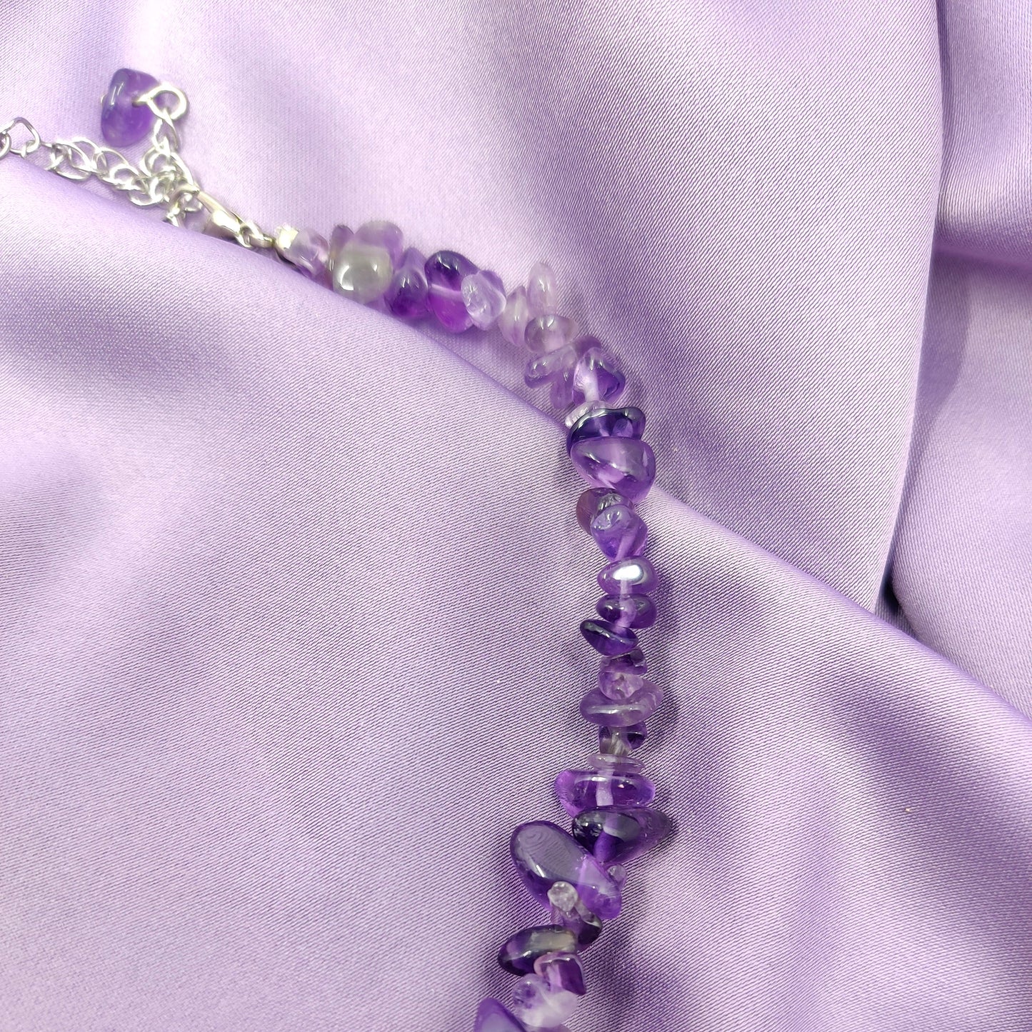 Violetin värinen ametistihippukaulakoru lähikuvassa violetilla taustalla