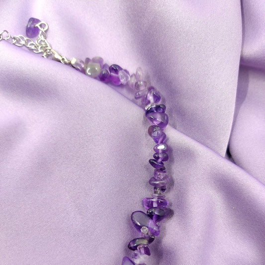 Violetin värinen ametistihippukaulakoru lähikuvassa violetilla taustalla