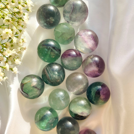 Vihreät ja violetit fluoriitti kivikuulat valkoisella taustalla