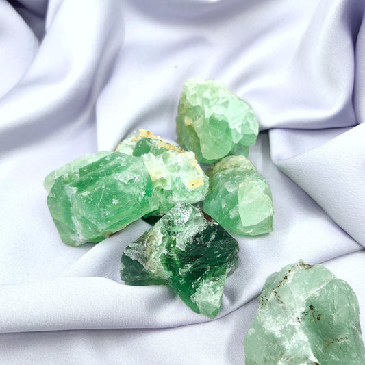 Vihreät fluoriitti raakapalat violettilla kankaalla