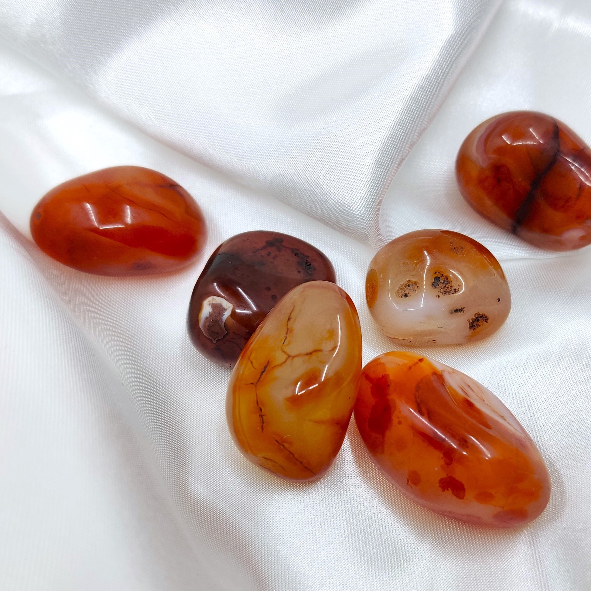 Rumpuhiottuja karneolikiviä valkoisella silkkikankaalla