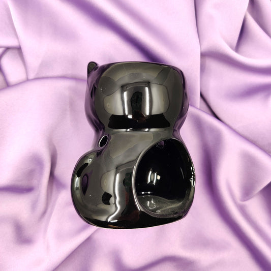 Musta kissa tuoksulyhty kuvattuna takaapäin violetilla taustalla