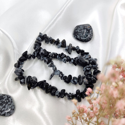 Mustavalkoiset lumihiutaleobsidiaani hippurannekorut kuvattuna kahden rumpuhiotun lumihiutaleobsidiaanin kanssa valkoisella taustalla