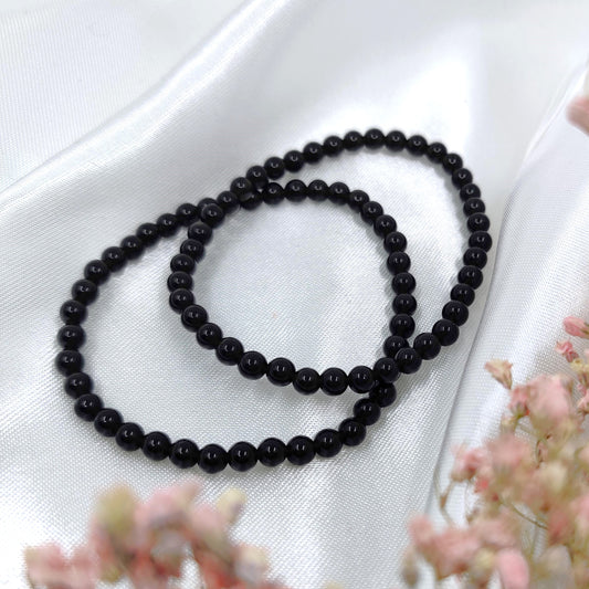 Syvän mustat obsidiaani helmirannekorut valkoisella taustalla
