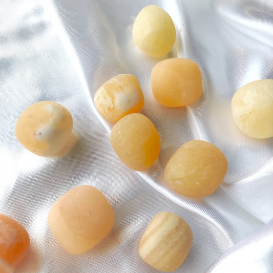 Rumpuhiottuja oransseja kalsiittikiviä valkoisella silkkikankaalla