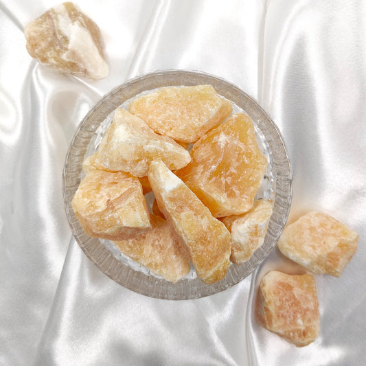 Oranssi kalsiitti raakapalat lasikulhossa valkoisella taustalla