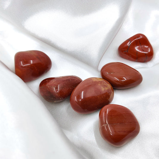 Rumpuhiottuja punaisia jaspiskiviä valkoisella silkkikankaalla