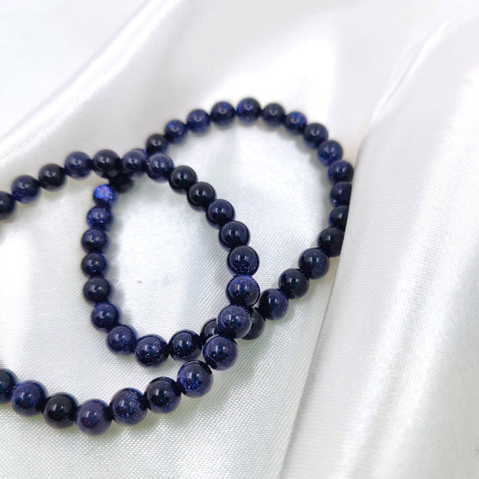 Kimaltavat sininen kultavirta helmirannekorut valkoisella silkkikankaalla