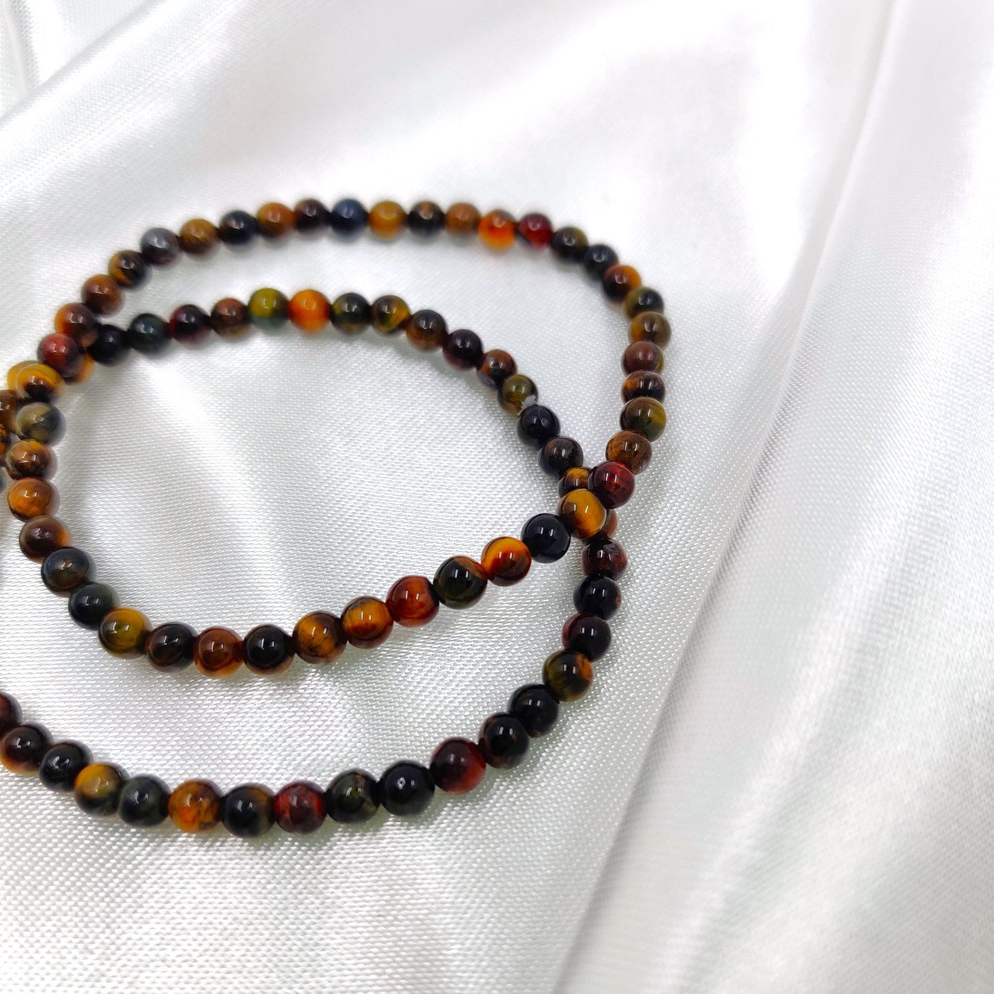 Tumman väriset tiikerinsilmä helmirannekorut valkoisella taustalla