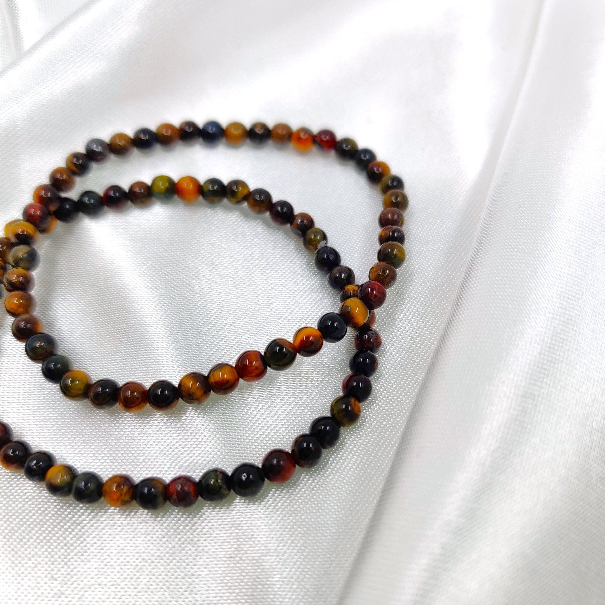 Tumman väriset tiikerinsilmä helmirannekorut valkoisella taustalla